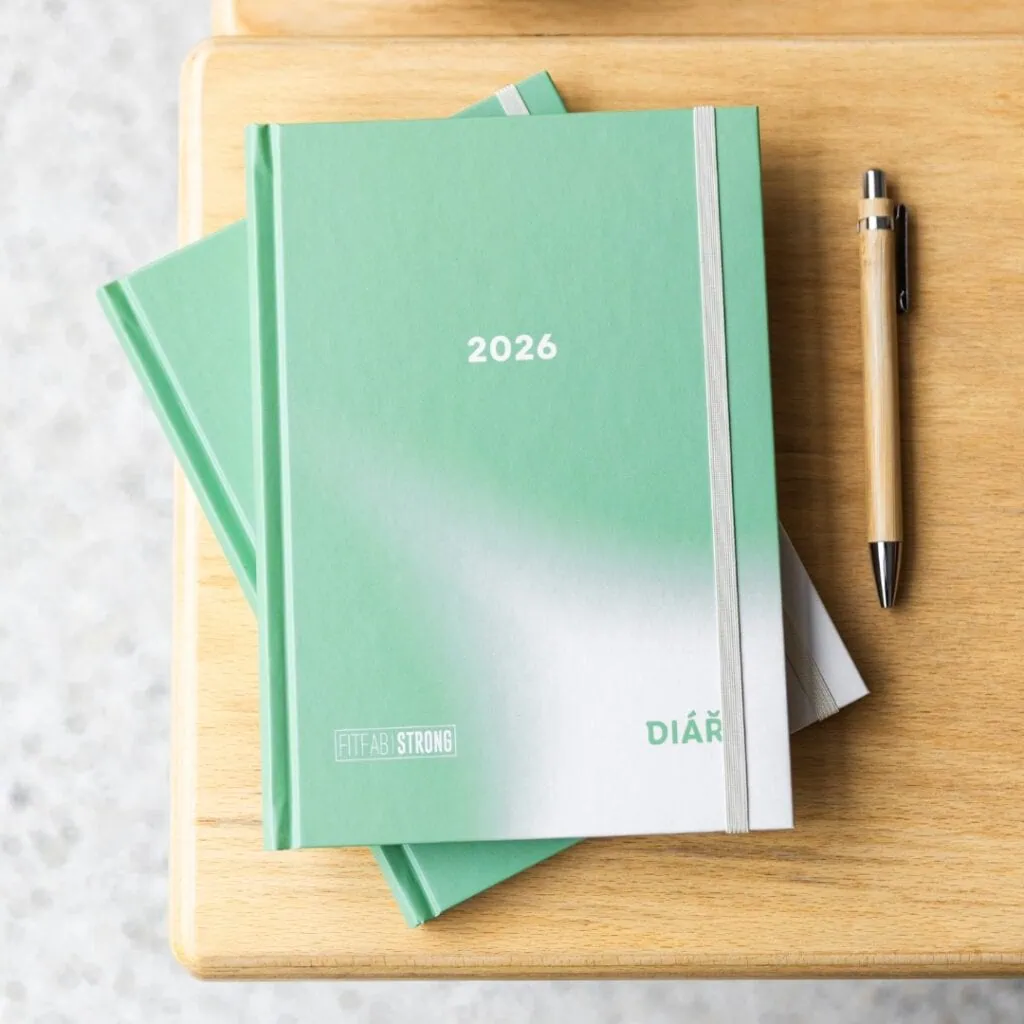 Tréninkový plán pro rok 2026 v zeleném diářu s nápisem "DIÁŘ" a propiskou vedle.