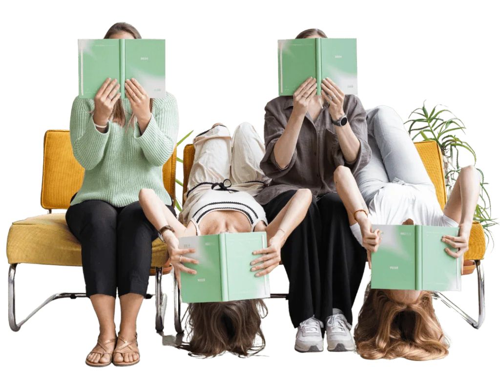 Čtyři ženy sedí na židlích, každá drží zelenou knihu před obličejem, v pozadí rostlina.