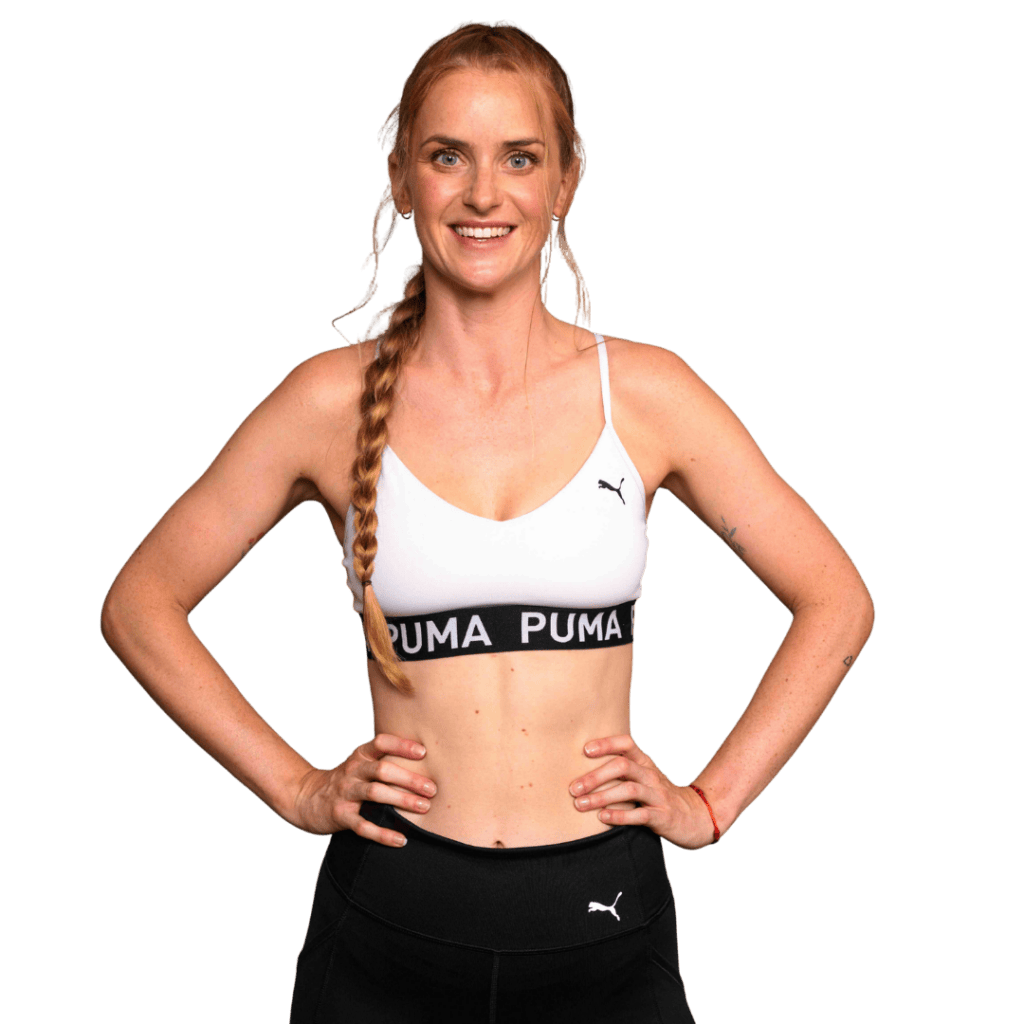 Žena v sportovním oblečení s dlouhým copem se usmívá a má ruce na bocích, připravena na trénink.